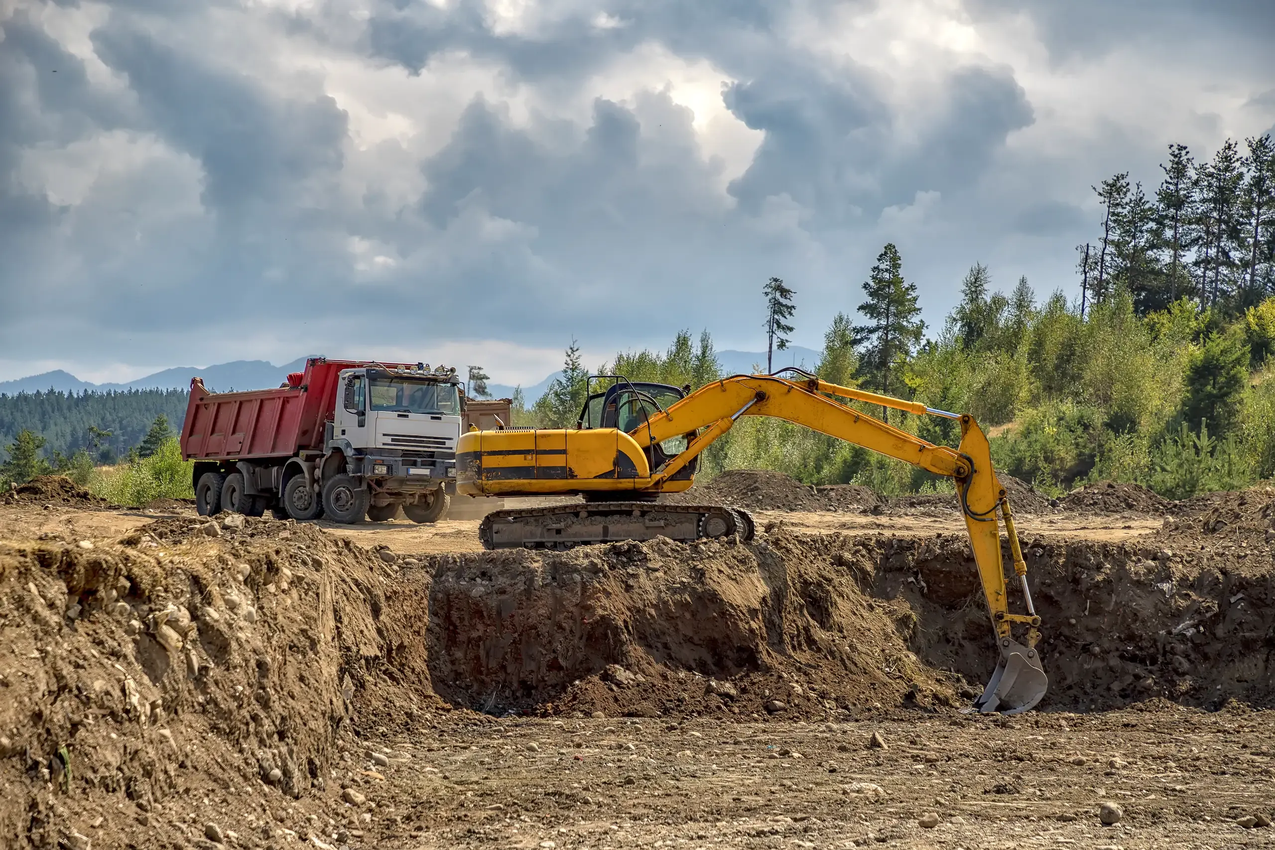 Prace ziemne z użyciem minikoparki i ciężarówki na terenie budowy