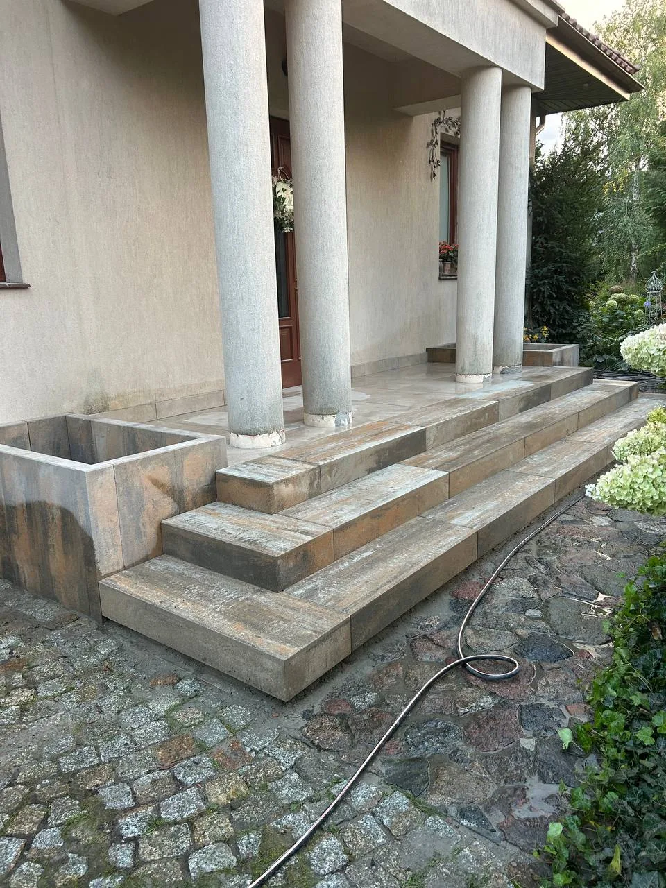 Schody zewnętrzne wykonane z płyt tarasowych prowadzące do wejścia domu