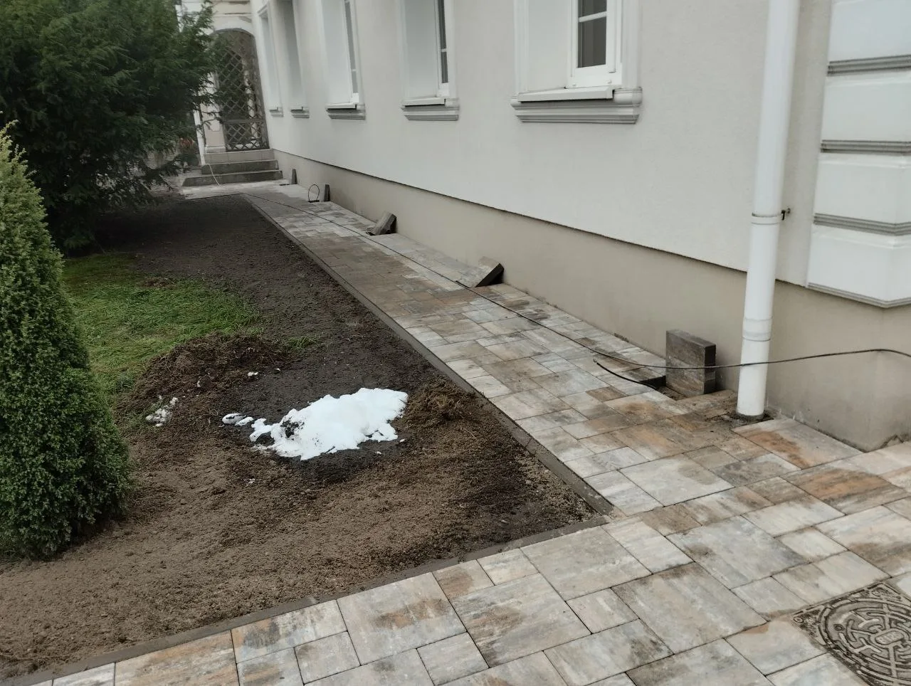 Układanie kostki brukowej na przygotowanym terenie z widocznym podłożem