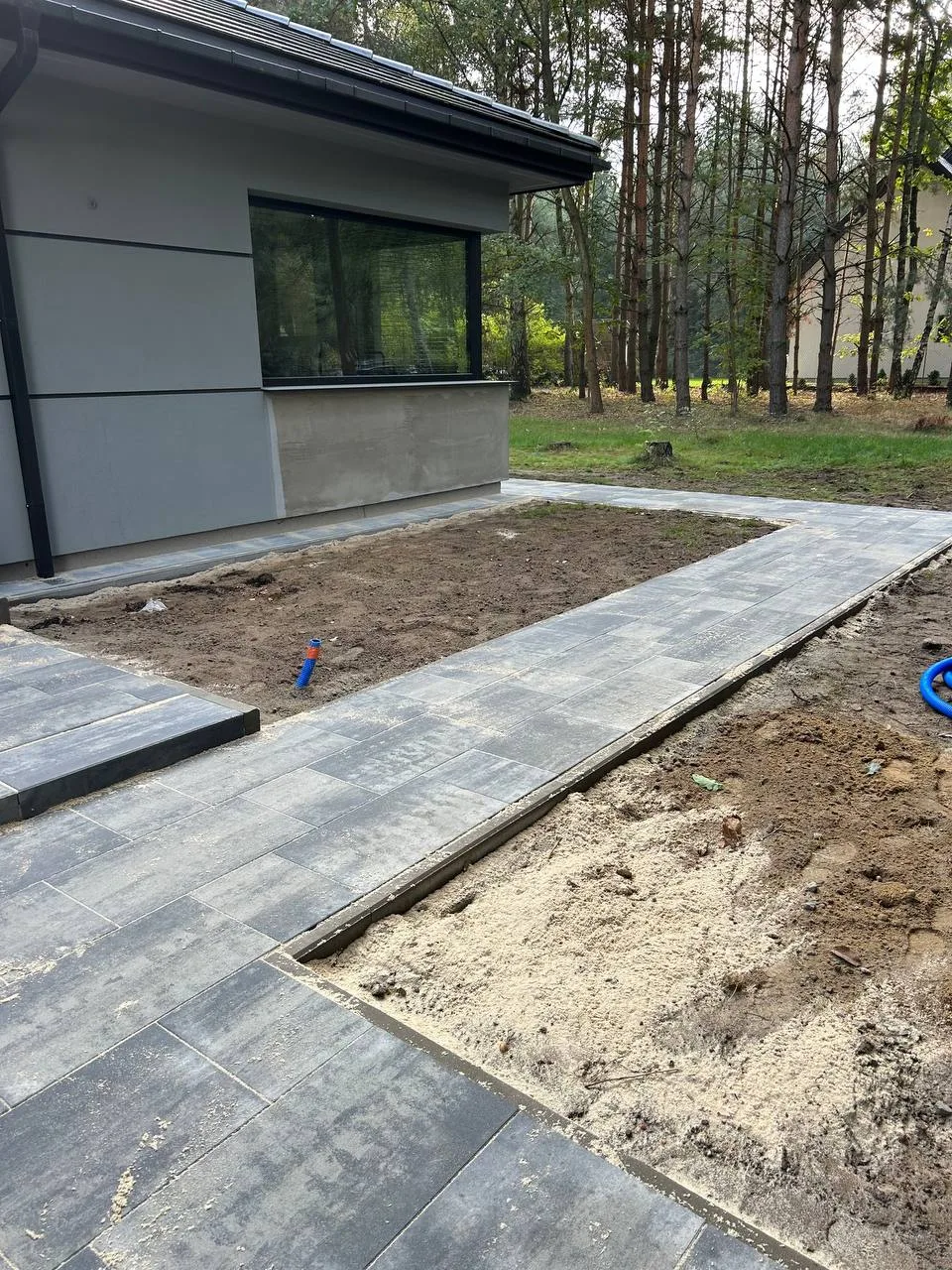 Przygotowanie terenu pod inwestycję z układaną kostką brukową. Widać obrzeża i wydzielone miejsce na taras