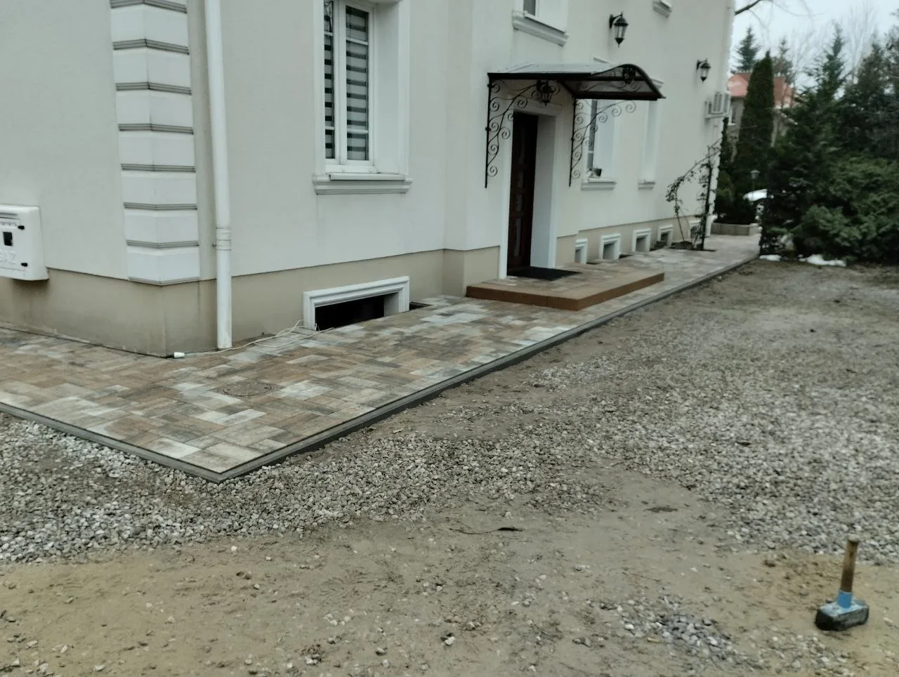 Układanie kostki brukowej przy wejściu do budynku oraz przygotowany teren